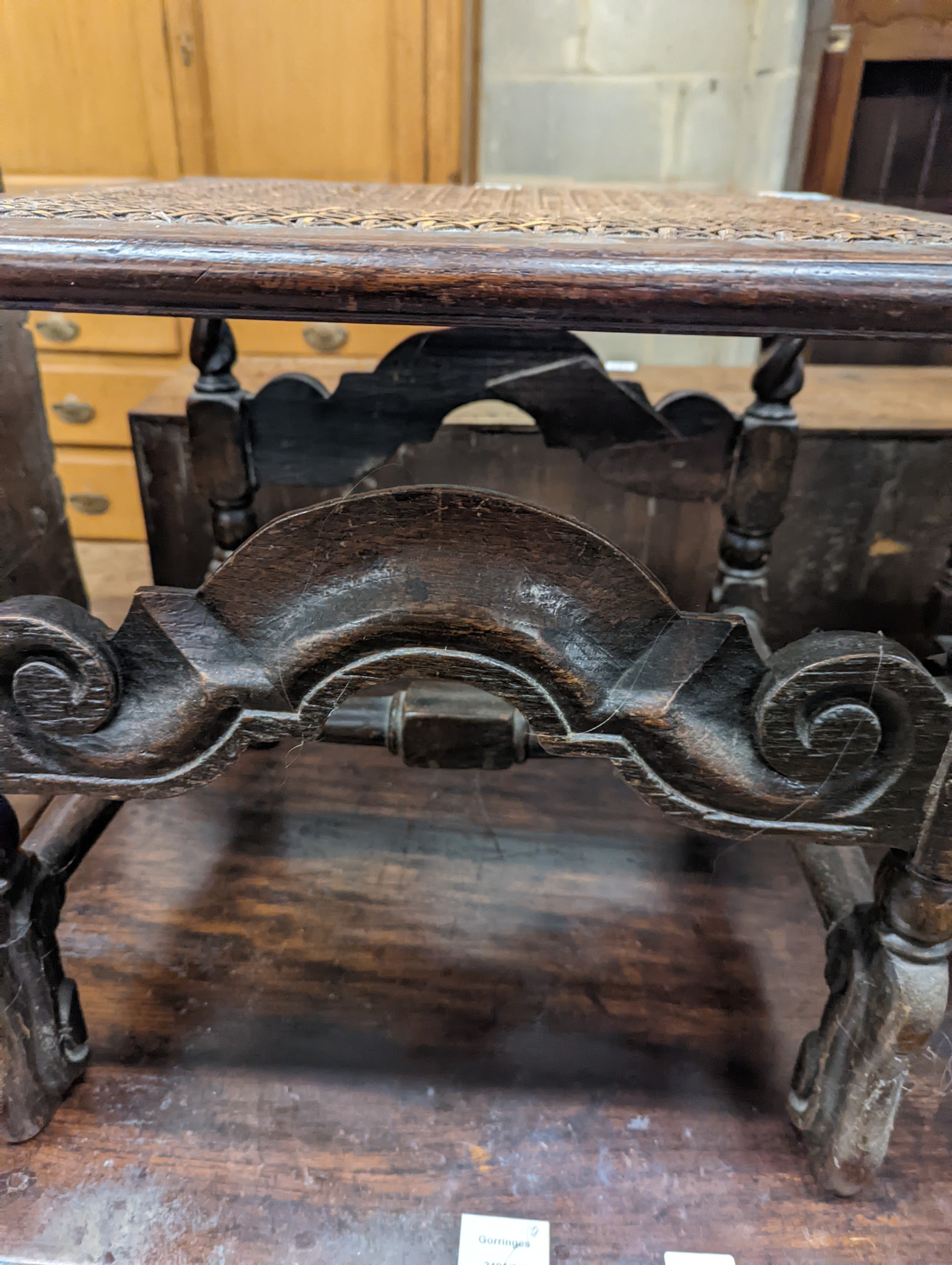 A 17th century style carved oak stool, with caned seat and H stretcher, width 47cm, depth 46cm, height 42cm